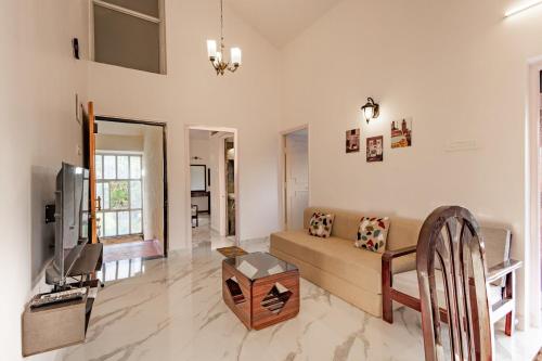 a living room with a couch and a tv at Modern 1BHK Condo With Pool 3min Walk To Beach in Orlim