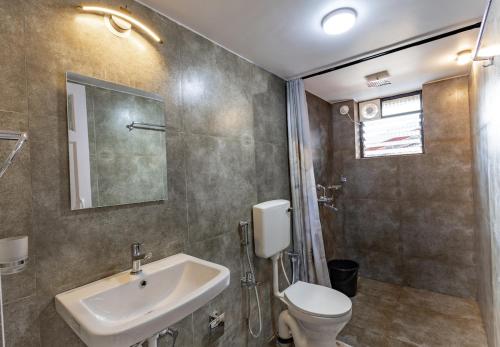 a bathroom with a sink and a toilet at Modern 1BHK Condo With Pool 3min Walk To Beach in Orlim