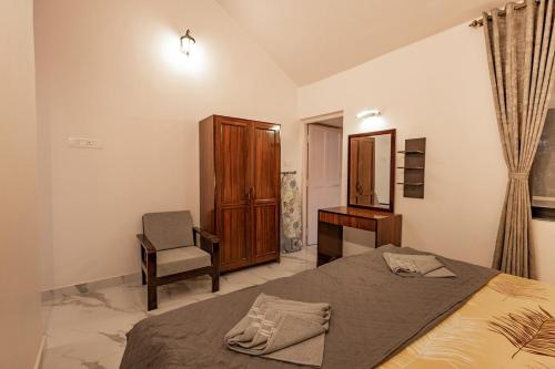 a bedroom with a bed and a chair and a desk at Modern 1BHK Condo With Pool 3min Walk To Beach in Orlim