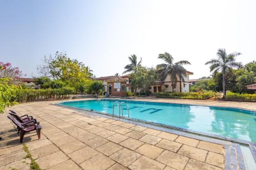 a swimming pool with a bench in front of a house at Modern 1BHK Condo With Pool 3min Walk To Beach in Orlim
