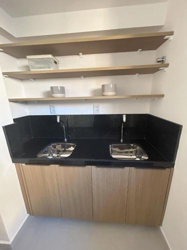 a kitchen with a black counter with two sinks at Aurea Bauten in João Pessoa