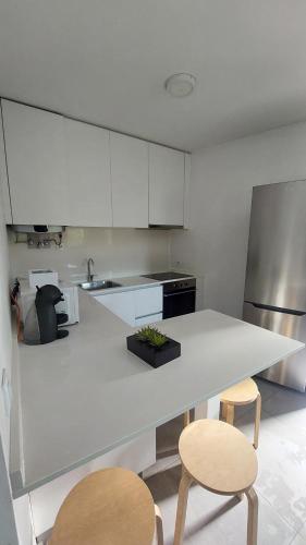 a kitchen with a white counter and two stools at Costa Guest House in Guimarães