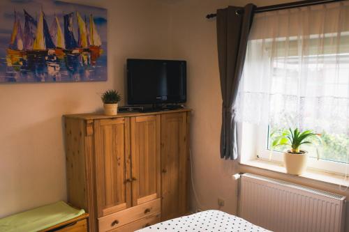 a bedroom with a tv on a wooden cabinet and a window at Kleine Mariken in Zingst