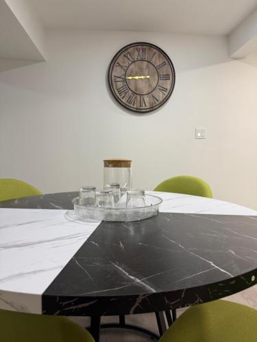 a black table with green chairs and a clock on the wall at THE GUEST HOUSE WEST EDMONTON Mall in Edmonton