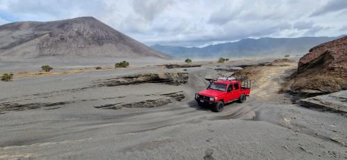 a red truck driving on a dirt road in the desert at Lava view Bungalows in Isaka