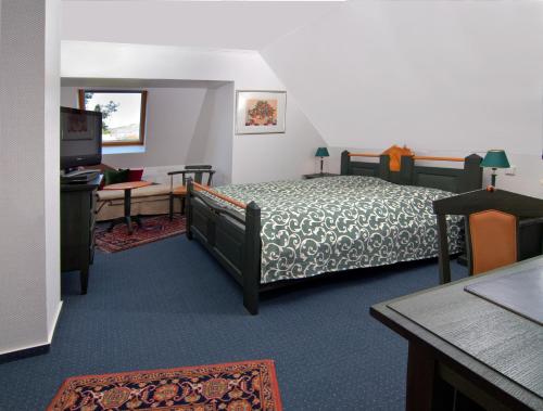 a bedroom with a bed and a desk and a television at BB Landhotel Hütter in Meschede