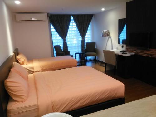 a bedroom with two beds and a desk and a television at Studio Apartment Kota Bharu (KBCP) in Kota Bharu