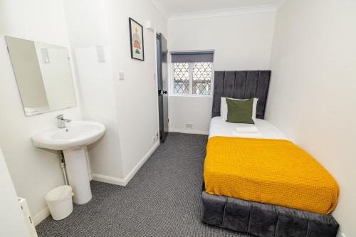 a small bedroom with a bed and a sink at Woodford Hotel in London
