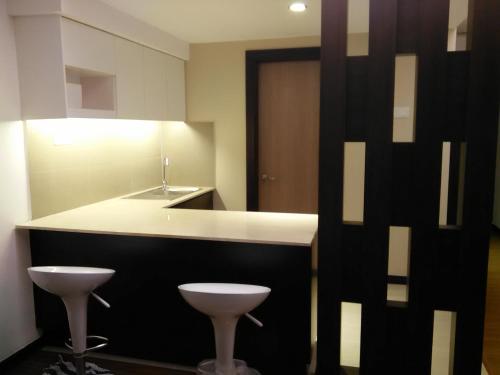 a kitchen with a sink and a counter with two stools at Studio Apartment Kota Bharu (KBCP) in Kota Bharu