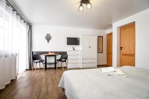 a white bedroom with a bed and a table at Willa Góry A - Noclegi z widokiem na góry śniadaniami i sauna in Bukowina Tatrzańska
