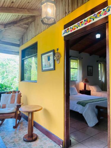 a bedroom with a bed and a yellow wall at Kakao Lodge & Garden Río Celeste in Bijagua