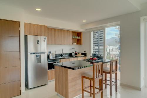 a kitchen with a stainless steel refrigerator and wooden cabinets at ¡Hermoso Condo con espectacular vista a la bahia!! in Puerto Vallarta