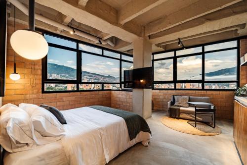 a bedroom with a large bed and large windows at Otalu Suites in Medellín