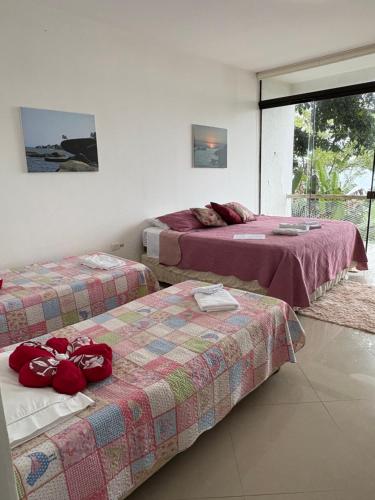 two beds in a hotel room with red pillows on them at CASA DE TUCA in Ilhabela