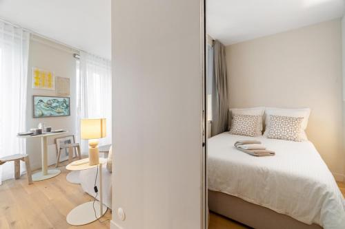 une chambre blanche avec un lit et un bureau dans l'établissement Appartement d'Architecte Design & Calme, à Paris