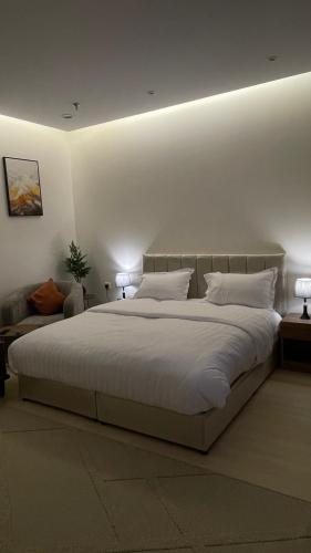 a bedroom with a large bed with white sheets and pillows at استديو فندقي واسع بالورود in Al Kharj