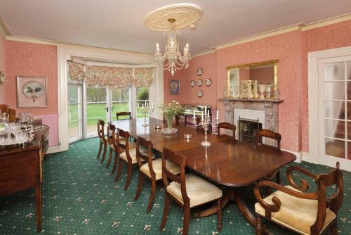 uma sala de jantar com uma mesa de madeira e cadeiras em Haughley House em Stowmarket