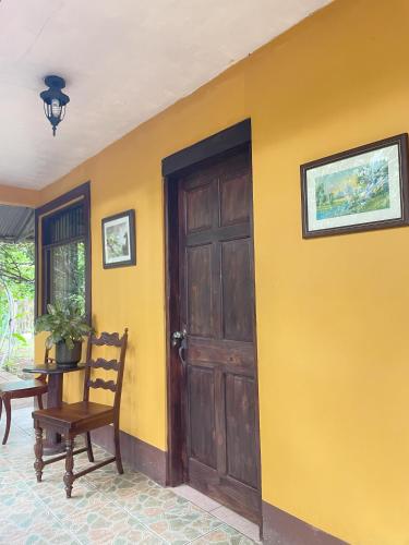 a yellow room with a wooden door and a table at Kakao Lodge & Garden Río Celeste in Bijagua