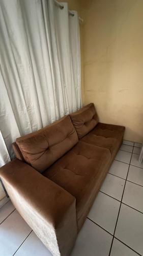 eine braune Couch vor einem Vorhang in der Unterkunft Suíte privativa com cozinha completa, ar e Wi-Fi in Palmas
