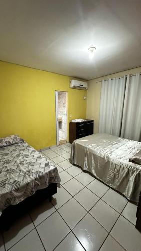 ein Schlafzimmer mit 2 Betten und einer gelben Wand in der Unterkunft Suíte privativa com cozinha completa, ar e Wi-Fi in Palmas