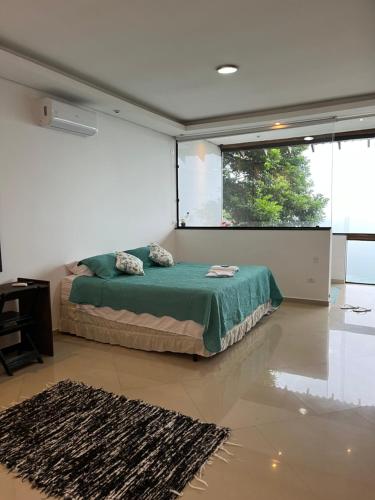 a bedroom with a bed and a large window at CASA DE TUCA in Ilhabela