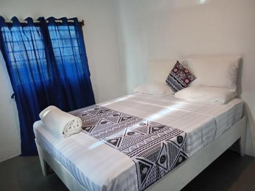 a bedroom with a bed with white sheets and blue curtains at Stephanie's Homestay in Matei