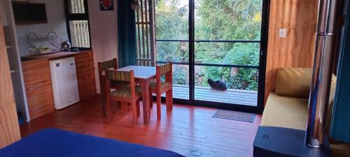 a kitchen with a table and chairs and a cat looking out the window at Posada IRSIS in La Pedrera