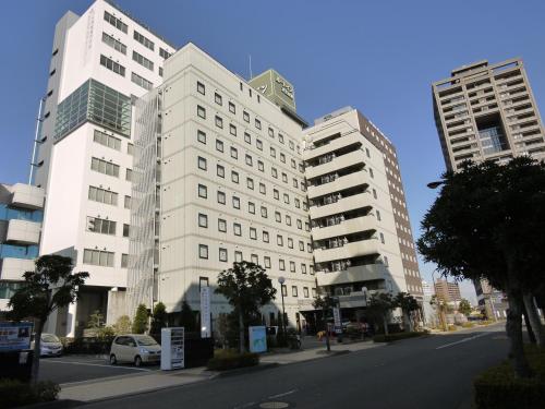 two tall white buildings on a city street at Hotel Route-Inn Hamamatsu Eki Higashi in Hamamatsu