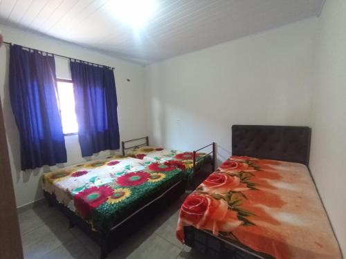 ein Schlafzimmer mit 2 Betten und einem Tisch mit Blumen in der Unterkunft Casa Porto Maringá in Marilena