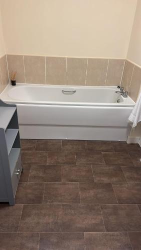 a white bath tub in a bathroom with a tile floor at Beautiful 2 bedroom apartment in lawley village in Lawley Bank