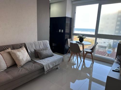 Una sala de estar con un sofá y una mesa con sillas. en Janela para o Mar, en Capão da Canoa