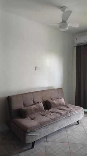 a brown couch in a room with a white wall at Pousada Tia Rosi com suites independente 100 mts da praia c ar, energia solar e atendimento vip in Rio das Ostras