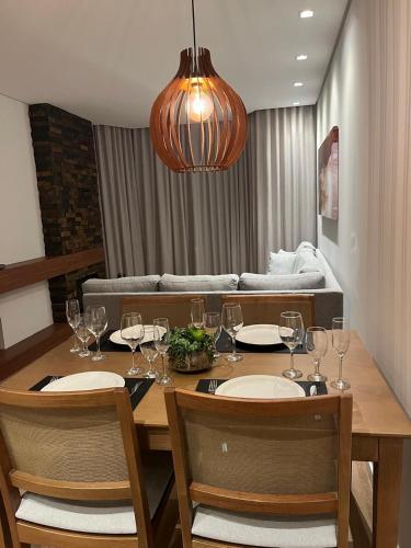 a dining room table with wine glasses and a couch at Aconchego Serra Class 205 Piscina, espaço kids, academia, sauna in Canela