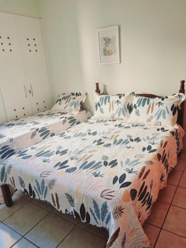 a bedroom with a bed with a floral comforter at Ed Ravena Com vista mar e elevador in Guarapari