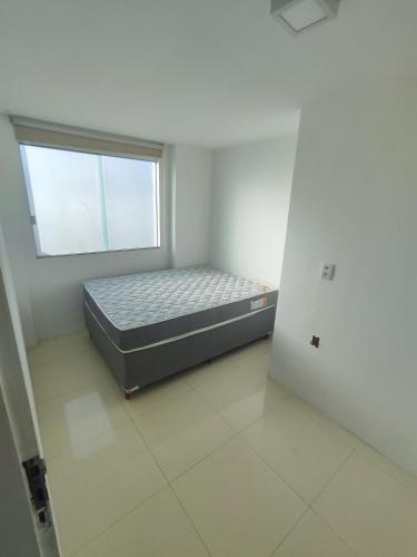 a bedroom with a bed in a room with a window at Village Beira mar in Lauro de Freitas