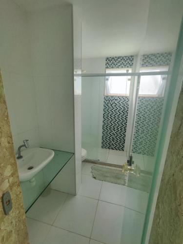 a white bathroom with a sink and a shower at Village Beira mar in Lauro de Freitas