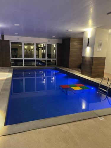 a large pool with blue water in a building at Aconchego Serra Class 205 Piscina, espaço kids, academia, sauna in Canela