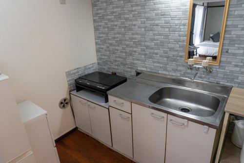 a small kitchen with a sink and a mirror at SORAHOME Direct access to city Manga & bicycle included in Tokyo