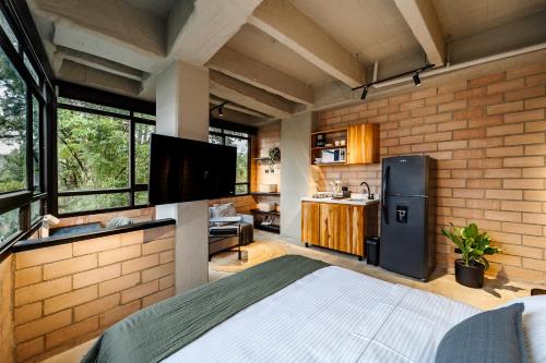 a room with a bed and a kitchen with a refrigerator at Otalu Suites in Medellín