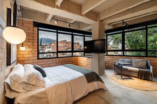 a bedroom with a large bed in a room with windows at Otalu Suites in Medellín