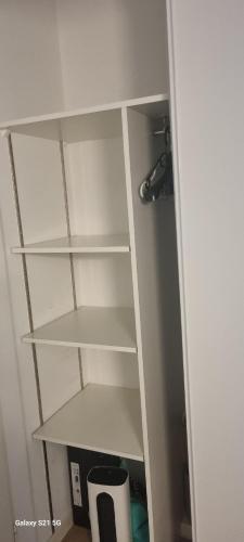 a white book shelf in a room at Le Repos Urbain-Grand T3 Cosy à 10 min de Paris & CDG in La Courneuve