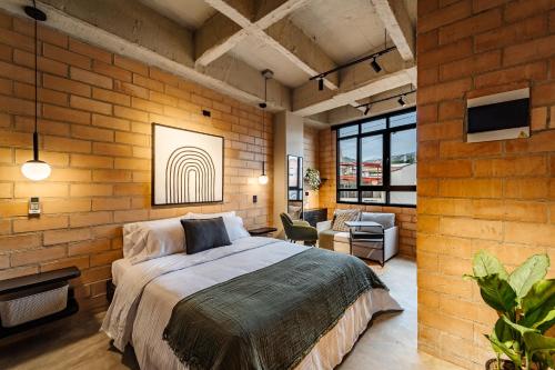 a bedroom with a bed and a brick wall at Otalu Suites in Medellín