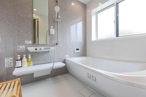 a bathroom with a tub and a sink and a window at Temple Hotel Kokushoji 宿坊 国昌寺 in Tsushima