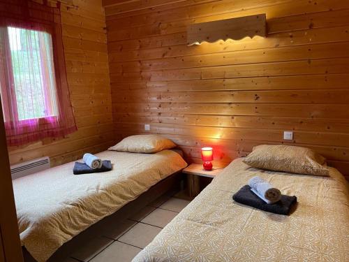 deux lits dans une cabane en rondins avec une bougie sur une table dans l'établissement Chalet spacieux à La Bresse, idéal pour familles et amis - FR-1-589-679, à La Bresse