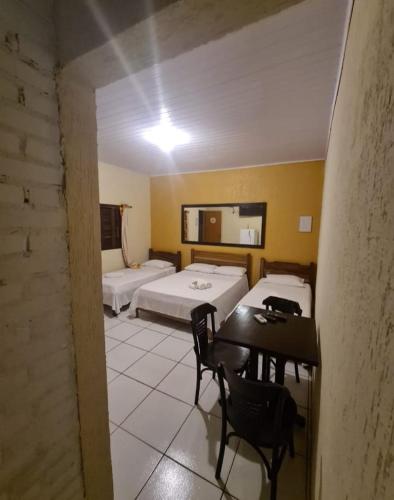 a room with two beds and a table and chairs at Pousada Refugio Prumirim in Ubatuba