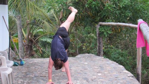 a woman doing a handstand on top of a rock at HOSTAL MIRADOR dentro del parque tayrona in El Zaino