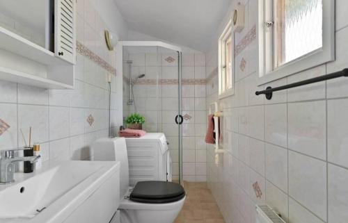 a white bathroom with a toilet and a sink at Cozy Social House Värmdö in Ingarö