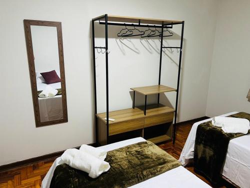 ein Zimmer mit zwei Betten und einem Spiegel in der Unterkunft Apto a 5 min da Basílica - 6 pessoas, Garagem, Wi-Fi in Aparecida