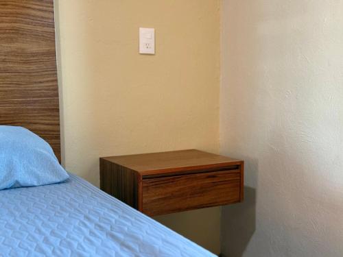 a bedroom with a bed and a wooden night stand at Villa La Palma Hotel in Tequila