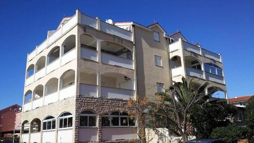 a tall white building with a tree in front of it at Apartment Palma - Novalja in Novalja